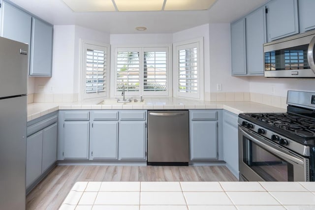 28328 Via Bandita, Menifee, CA 92585 - kitchen with stainless steel appliances, light wood-style flooring, and tile countertops