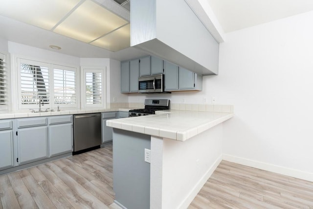 28328 Via Bandita, Menifee, CA 92585 - kitchen featuring stainless steel appliances, light wood finished floors, a peninsula, and tile counters