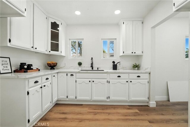 14581460 W 80th St, Los Angeles, CA 90047 - kitchen with white cabinetry, light wood-type flooring, recessed lighting, glass insert cabinets, and light stone counters