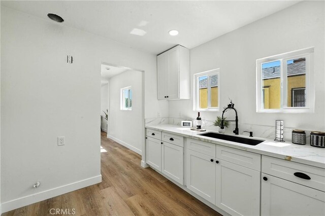 14581460 W 80th St, Los Angeles, CA 90047 - kitchen with light wood-type flooring, white cabinets, and light stone counters