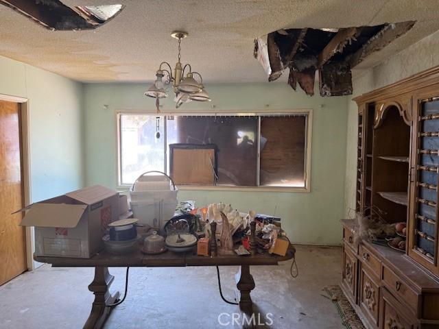 2089 Monterey Peninsula Dr, Corona, CA 92882 - dining space featuring concrete floors, a textured ceiling, and a chandelier