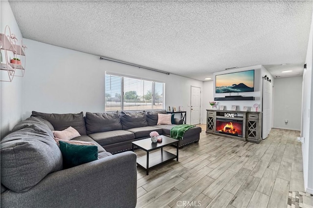 18396 Live Oak St, Hesperia, CA 92345 - living room featuring light wood finished floors, a textured ceiling, and a lit fireplace
