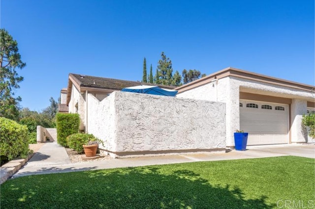 814 Cardamom Ct, Chula Vista, CA 91910 - view of side of home featuring a garage, stucco siding, driveway, and a yard