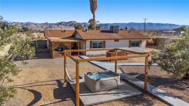 63608 Jadeite St, Joshua Tree, CA 92252 - rear view of property featuring a deck with mountain view, stucco siding, and a hot tub