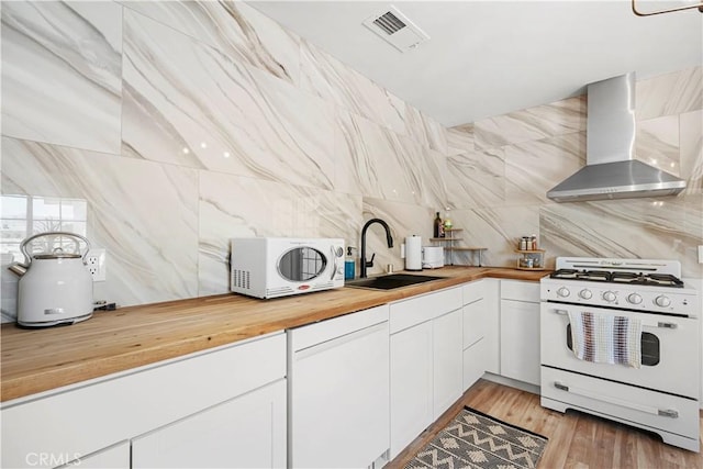 63608 Jadeite St, Joshua Tree, CA 92252 - kitchen featuring wall chimney exhaust hood, white appliances, butcher block countertops, decorative backsplash, and white cabinets