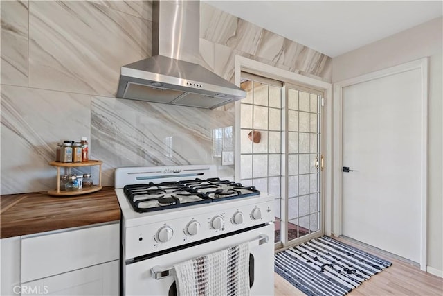 63608 Jadeite St, Joshua Tree, CA 92252 - kitchen with white range with gas cooktop, wall chimney exhaust hood, butcher block counters, and light wood-style flooring