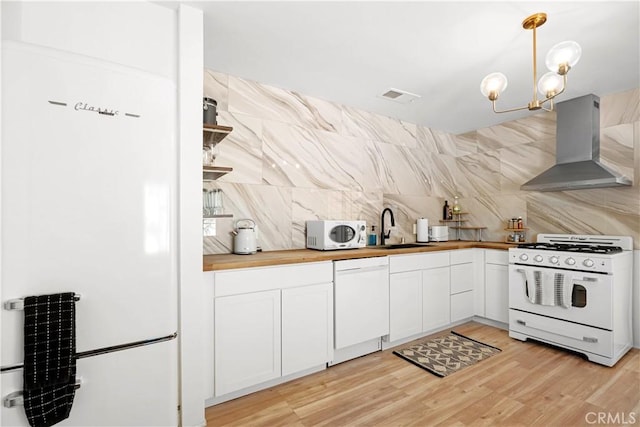 63608 Jadeite St, Joshua Tree, CA 92252 - kitchen with white appliances, wall chimney range hood, wooden counters, decorative backsplash, and white cabinets