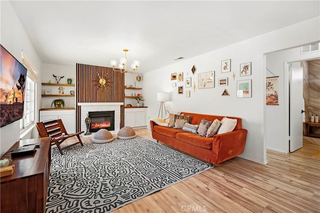 63608 Jadeite St, Joshua Tree, CA 92252 - living area featuring wood finished floors, a chandelier, and a glass covered fireplace