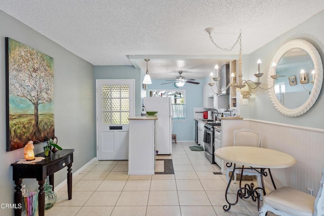 130 E Bay Blvd, Port Hueneme, CA 93041 - kitchen featuring freestanding refrigerator, a textured ceiling, light tile patterned flooring, a wainscoted wall, and gas range
