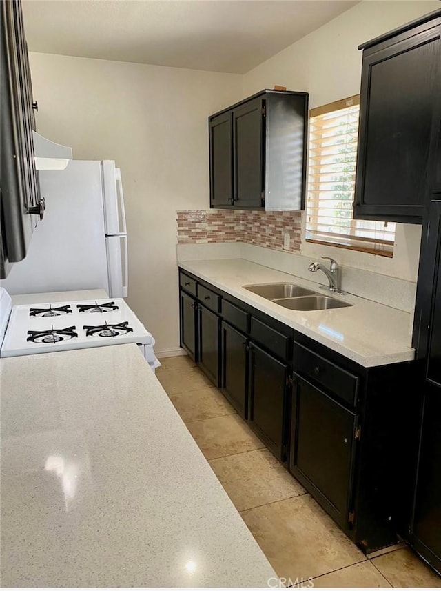 1303 W 109th Pl, Los Angeles, CA 90044 - kitchen with light countertops, dark cabinetry, white appliances, tasteful backsplash, and range hood