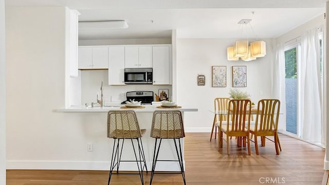 13133 Le Parc Unit 503, Chino Hills, CA 91709 - kitchen featuring stainless steel microwave, stove, a kitchen breakfast bar, light wood-type flooring, and white cabinets
