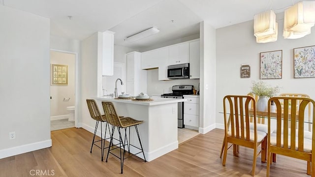 13133 Le Parc Unit 503, Chino Hills, CA 91709 - kitchen featuring stainless steel appliances, light wood-style floors, white cabinetry, and a kitchen bar