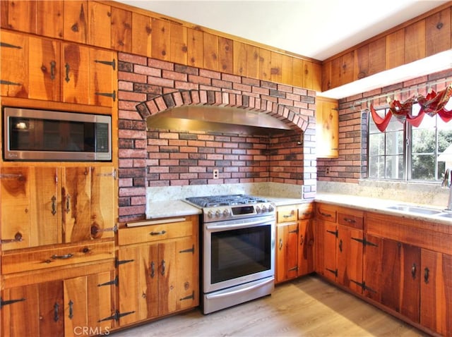 1023 Fremont St, Calimesa, CA 92320 - kitchen with appliances with stainless steel finishes, range hood, light countertops, light wood-style floors, and brown cabinets