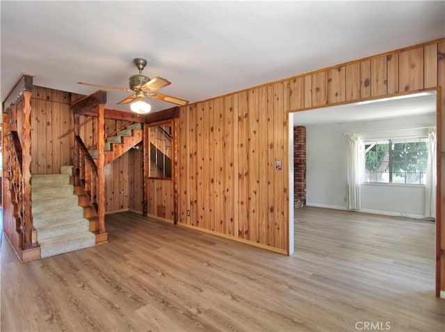 1023 Fremont St, Calimesa, CA 92320 - unfurnished living room featuring wooden walls, stairs, ceiling fan, and wood finished floors