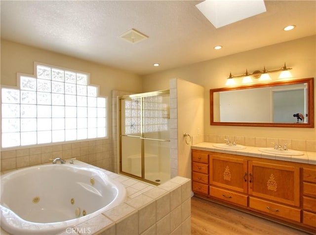 1023 Fremont St, Calimesa, CA 92320 - bathroom with a shower stall, a jetted tub, double vanity, wood finished floors, and a skylight
