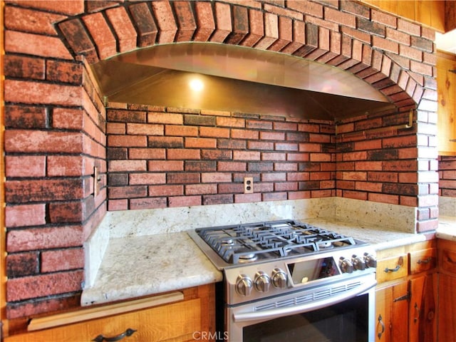 1023 Fremont St, Calimesa, CA 92320 - kitchen with stainless steel range with gas stovetop, brown cabinetry, and brick wall