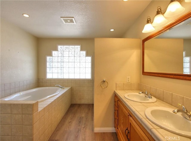 1023 Fremont St, Calimesa, CA 92320 - full bathroom with wood finished floors, plenty of natural light, a garden tub, double vanity, and recessed lighting