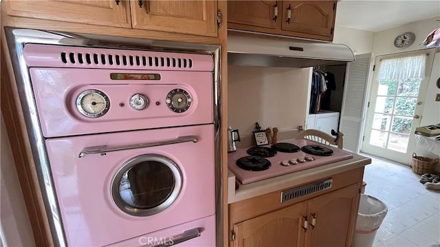 14020 Avion Dr, La Mirada, CA 90638 - kitchen with under cabinet range hood, stacked washer / dryer, white stovetop, and double wall oven