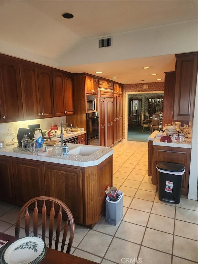 3082 Copa De Oro Dr, Los Alamitos, CA 90720 - kitchen with tile counters, light tile patterned floors, built in appliances, a peninsula, and vaulted ceiling