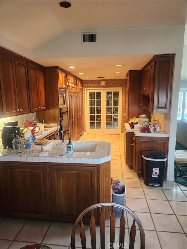 3082 Copa De Oro Dr, Los Alamitos, CA 90720 - kitchen featuring tile counters, light tile patterned flooring, lofted ceiling, a peninsula, and backsplash