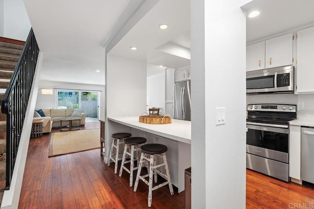 1833 Stonebrook Ln, Encinitas, CA 92024 - kitchen featuring stainless steel appliances, white cabinetry, dark wood-type flooring, a breakfast bar area, and recessed lighting