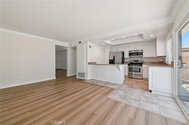 1984 Mount Shasta Dr, San Pedro, CA 90732 - kitchen featuring stainless steel appliances, crown molding, a peninsula, light wood-type flooring, and a kitchen bar