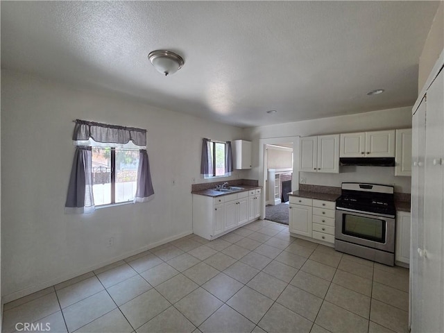 521 E 7th St, National City, CA 91950 - kitchen with stainless steel gas range oven, under cabinet range hood, white cabinets, light tile patterned floors, and dark countertops