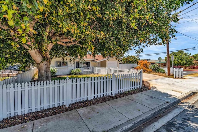 552 Emory St, Imperial Beach, CA 91932 - view of property hidden behind natural elements with a fenced front yard, concrete driveway, and a garage