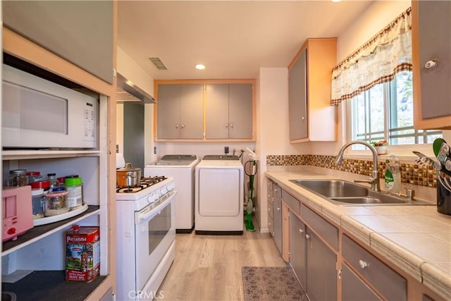 24561 Sinaloa St, Moreno Valley, CA 92557 - kitchen featuring white appliances, washing machine and clothes dryer, light wood-style floors, recessed lighting, and tile countertops