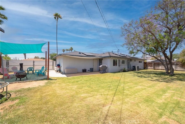 24561 Sinaloa St, Moreno Valley, CA 92557 - rear view of property featuring a fire pit, stucco siding, roof mounted solar panels, a fenced backyard, and a patio