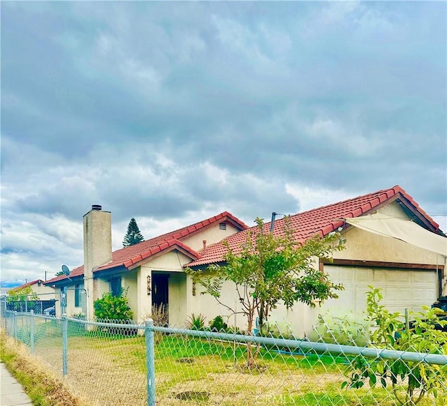 895 Garner Ave, San Bernardino, CA 92411 - view of front of house featuring a garage, a tile roof, a chimney, and stucco siding