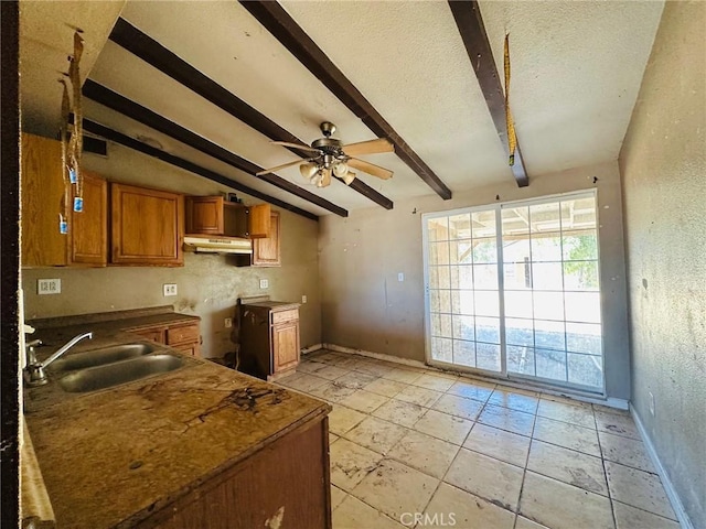 27331 Perkins Rd, Madera, CA 93637 - kitchen with brown cabinetry, beamed ceiling, under cabinet range hood, a ceiling fan, and a textured ceiling