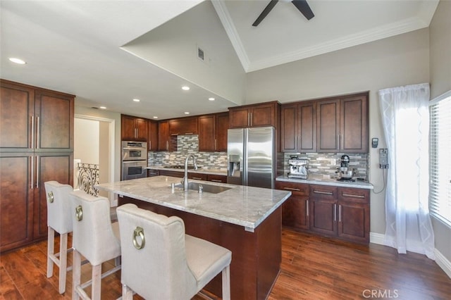 38 Toulon, Laguna Niguel, CA 92677 - kitchen with appliances with stainless steel finishes, ornamental molding, backsplash, light stone countertops, and an island with sink