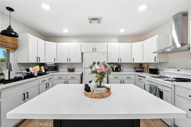9562 Locust Ave, Fontana, CA 92335 - kitchen with white appliances, wall chimney exhaust hood, light countertops, white cabinets, and decorative light fixtures