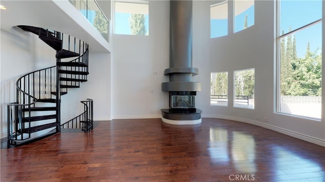 22500 N Summit Ridge Cir, Chatsworth, CA 91311 - unfurnished living room featuring a high ceiling, wood finished floors, stairway, and a wood stove