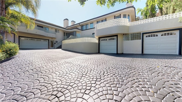 22500 N Summit Ridge Cir, Chatsworth, CA 91311 - view of front of home featuring stucco siding, decorative driveway, and a garage