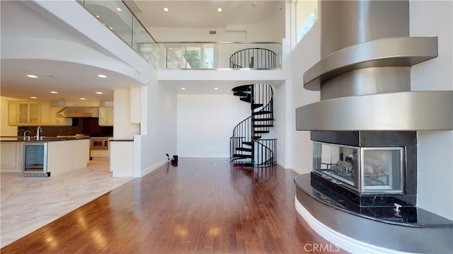 22500 N Summit Ridge Cir, Chatsworth, CA 91311 - living room featuring wine cooler, a multi sided fireplace, stairway, a high ceiling, and light wood-style flooring