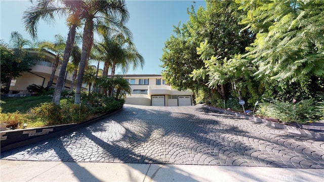 22500 N Summit Ridge Cir, Chatsworth, CA 91311 - view of property hidden behind natural elements with a garage, decorative driveway, and stucco siding