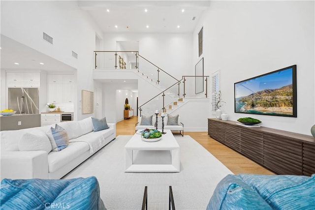 101 Lustro, Irvine, CA 92602 - living area featuring a towering ceiling, light wood-style flooring, stairway, recessed lighting, and beverage cooler