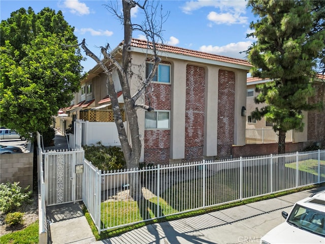 10155 De Soto Ave Unit 104, Chatsworth, CA 91311 - view of front of house featuring brick siding, a tile roof, and a fenced front yard