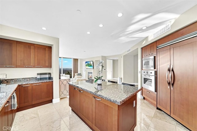 5124 Scholarship Unit 1007, Irvine, CA 92612 - kitchen with built in appliances, a center island, light stone counters, brown cabinetry, and recessed lighting