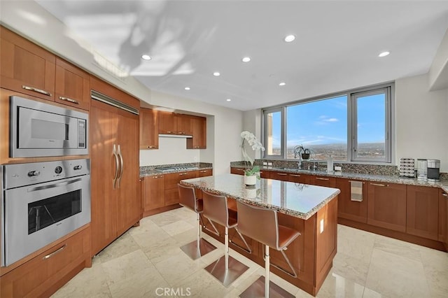 5124 Scholarship Unit 1007, Irvine, CA 92612 - kitchen featuring built in appliances, brown cabinets, a center island, recessed lighting, and light stone counters