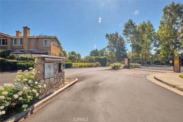 25401 Holly Beach Dr, Saugus, CA 91350 - view of asphalt street featuring a gated entry, curbs, sidewalks, and a gate