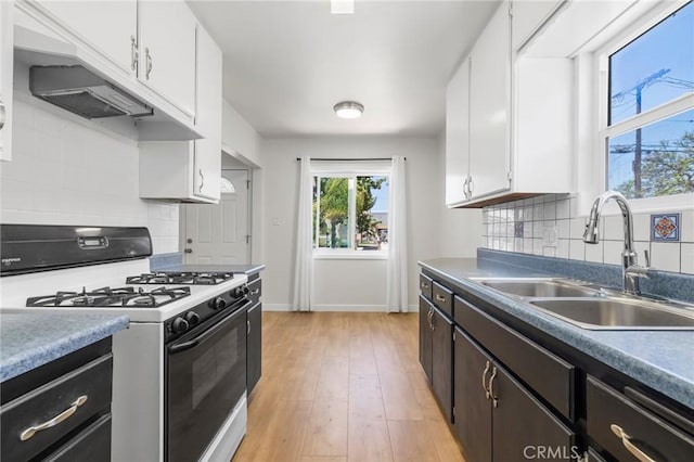 1410 Gulf Ave, Wilmington, CA 90744 - kitchen with white gas range, white cabinets, backsplash, and light wood finished floors