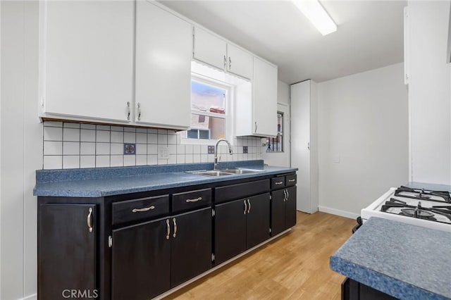 1410 Gulf Ave, Wilmington, CA 90744 - kitchen featuring white cabinets, light wood finished floors, tasteful backsplash, dark cabinetry, and gas range gas stove
