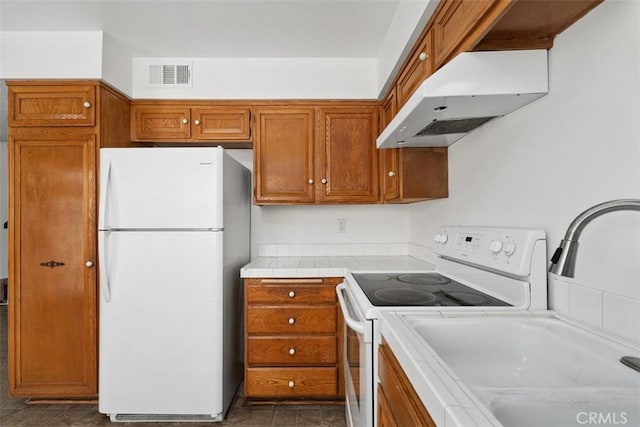 6150 Montecito Dr Unit 6, Palm Springs, CA 92264 - kitchen with white appliances, under cabinet range hood, tile countertops, and brown cabinetry