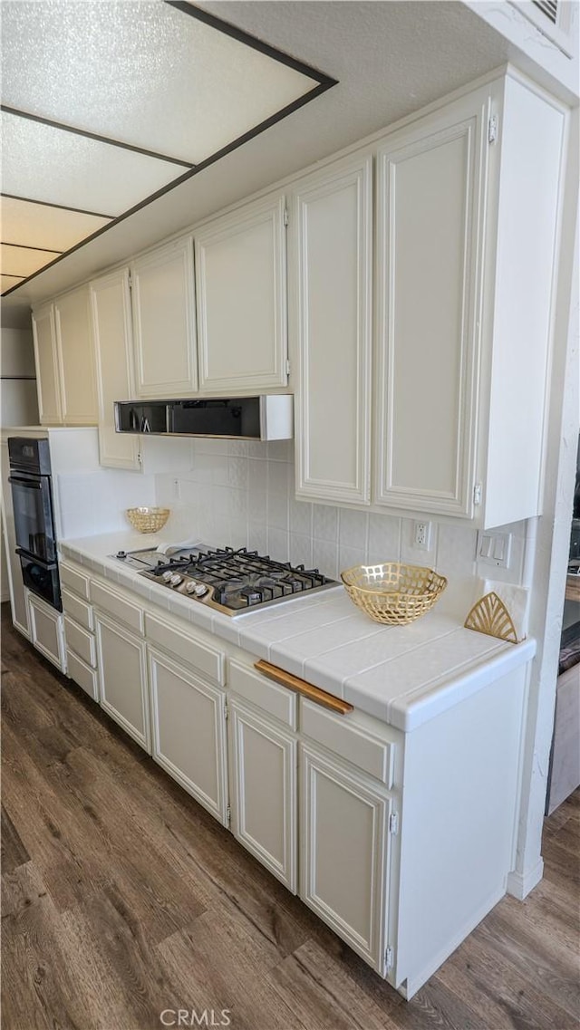 5310 Zelzah Ave Unit 312, Encino, CA 91316 - kitchen featuring stainless steel gas stovetop, dark wood-style floors, tile countertops, white cabinetry, and black oven