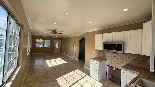9206 Elizabeth Ave, South Gate, CA 90280 - kitchen featuring stainless steel microwave, recessed lighting, arched walkways, ornamental molding, and backsplash