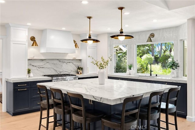 21210 Twin Oak, Yorba Linda, CA 92886 - kitchen featuring custom range hood, decorative backsplash, light wood-style flooring, light stone counters, and a breakfast bar