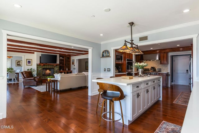 3626 Saint Elizabeth Rd, Glendale, CA 91206 - kitchen featuring wall chimney range hood, stainless steel appliances, light countertops, a tile fireplace, and a kitchen breakfast bar
